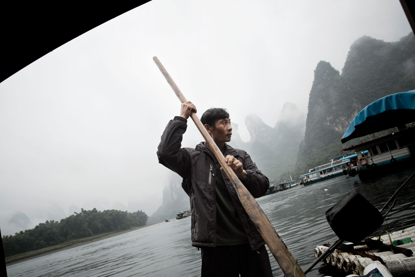 CHINA. Guangxi Province, September 2012. A man conduct a bamboo boat on the Li River.